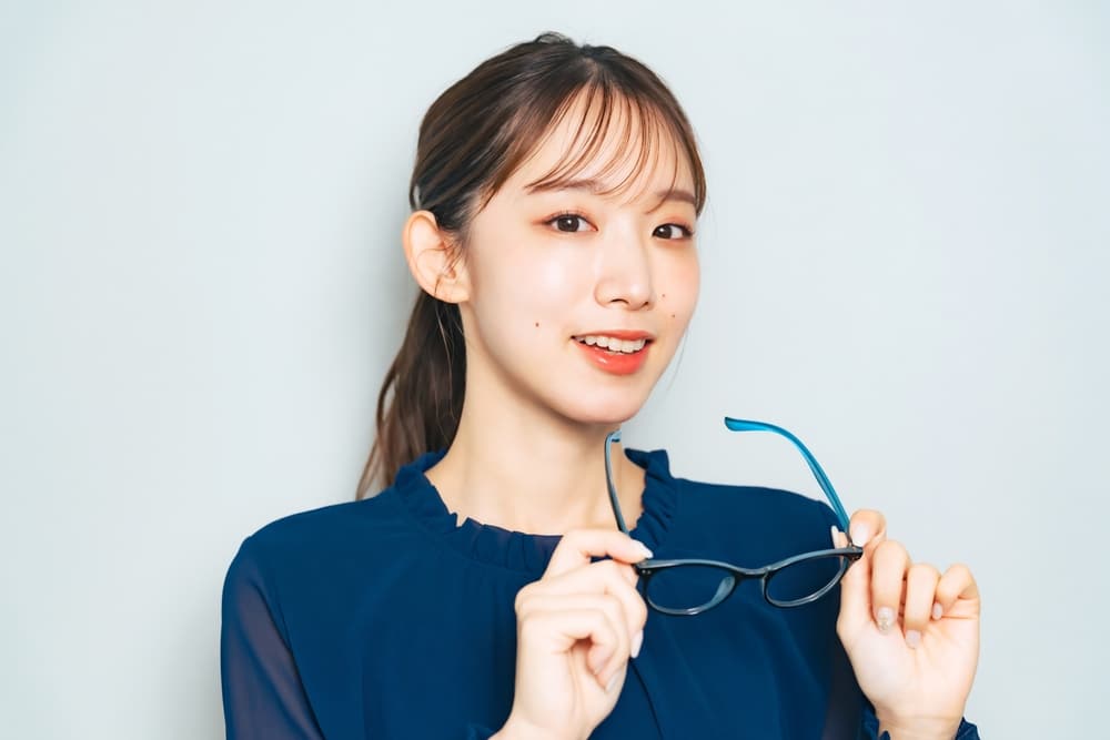 Woman holds her eyeglasses as she considers PRK vs LASIK in Austin